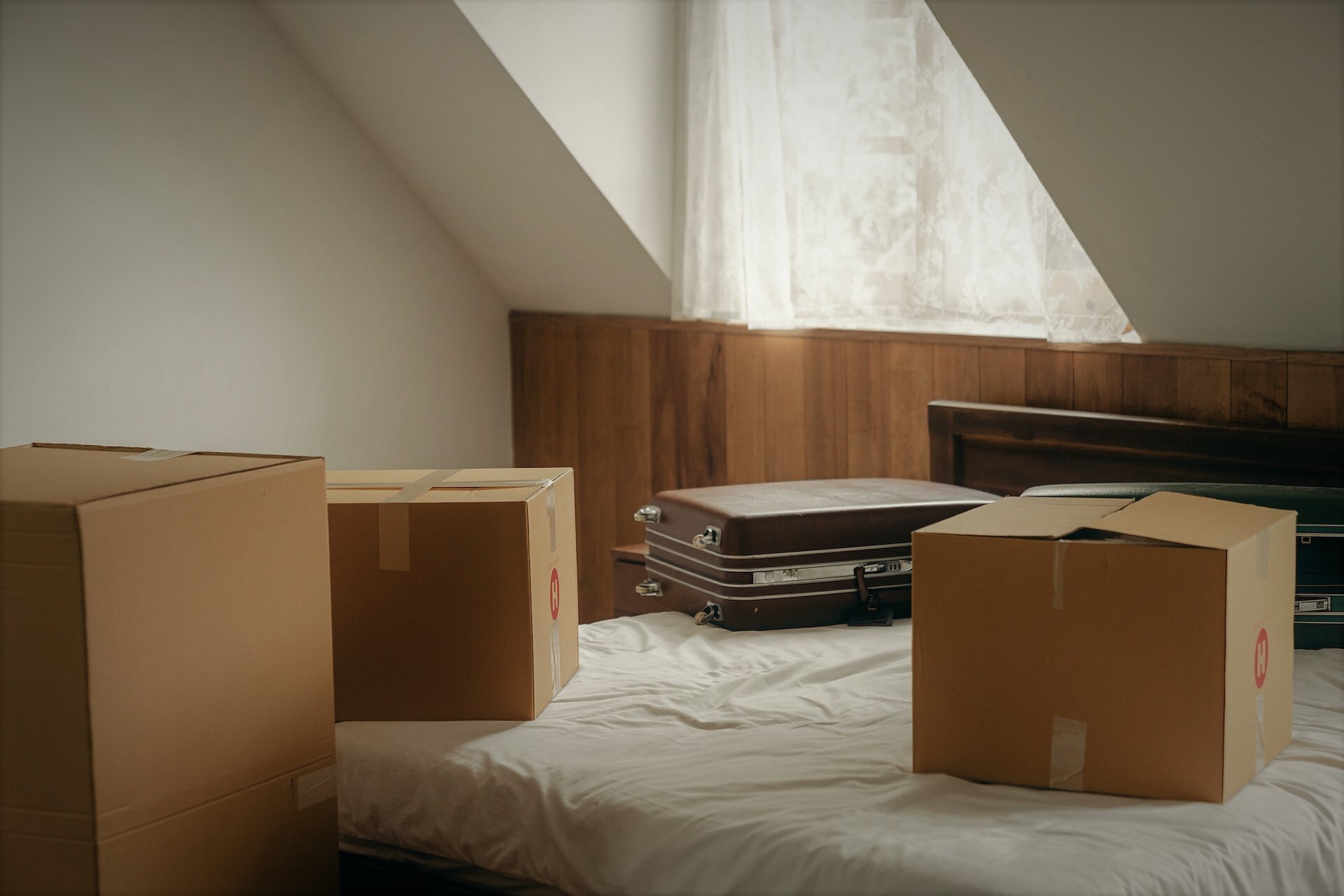 verhuisdozen en koffer op een bed in een lichte kamer